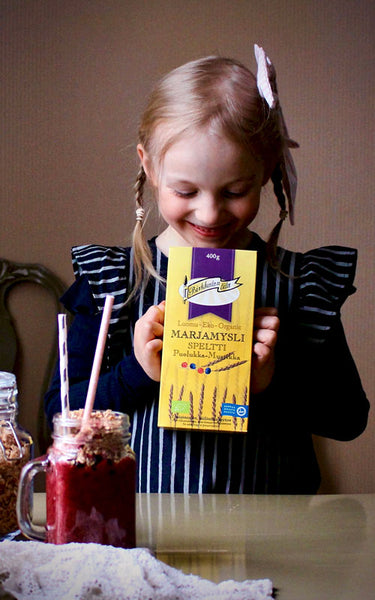 Birkkalan luomu speltti marja mysli smoothie annos ja pakkaus tytön käsissä.